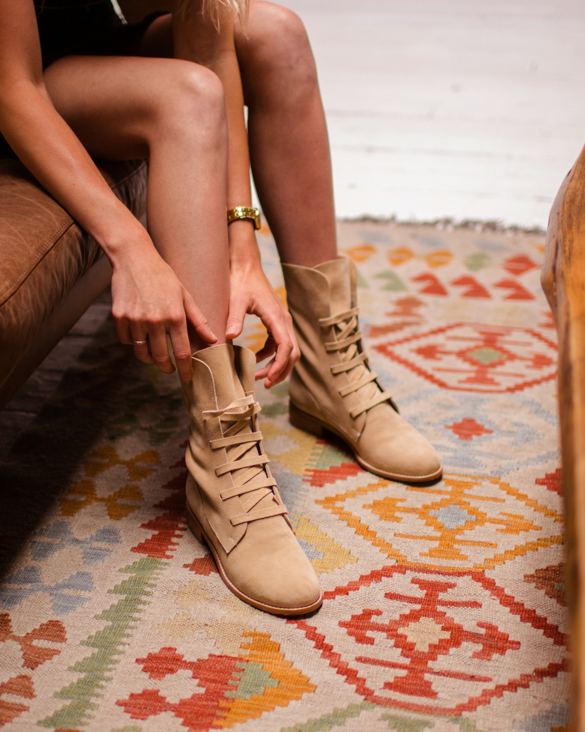 woman in brown leather peep toe heeled shoes sitting on brown leather couch